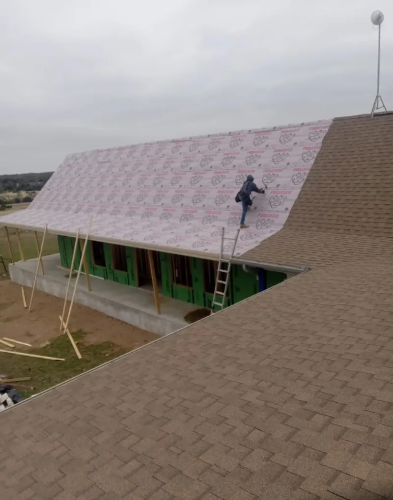 Worker preparing underlayment for a metal roof installation in Scott